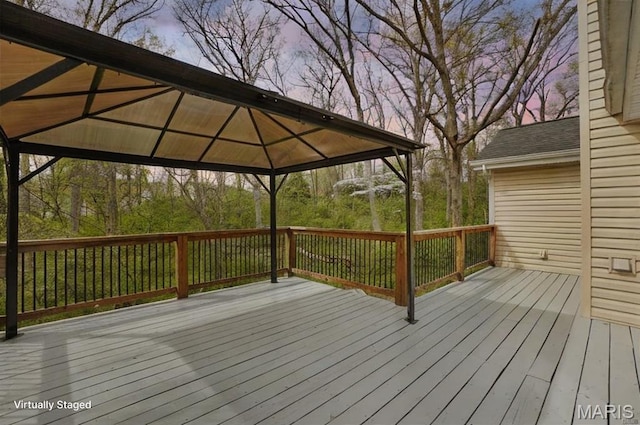 deck at dusk featuring a gazebo