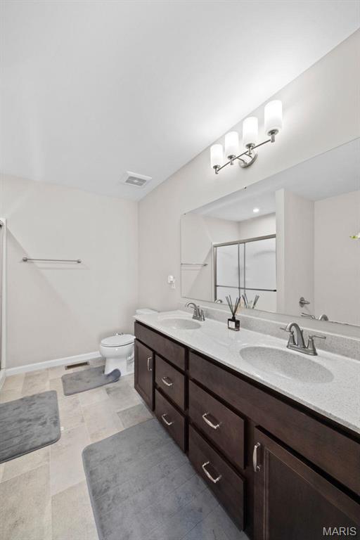 905 Sugar Pear St, Saint Charles, MO 63301 - full bathroom with double vanity, a stall shower, toilet, and baseboards