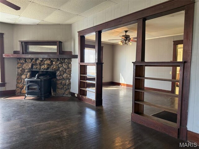 1681 S US Highway 63, West Plains, MO 65775 - unfurnished living room with ceiling fan, a wood stove, hardwood / wood-style floors, baseboards, and wooden walls