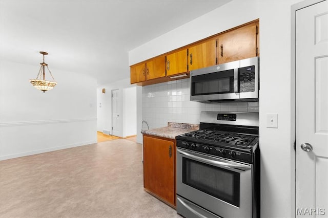 304 S Augusta St, Ofallon, IL 62269 - kitchen with appliances with stainless steel finishes, brown cabinetry, decorative backsplash, light countertops, and pendant lighting