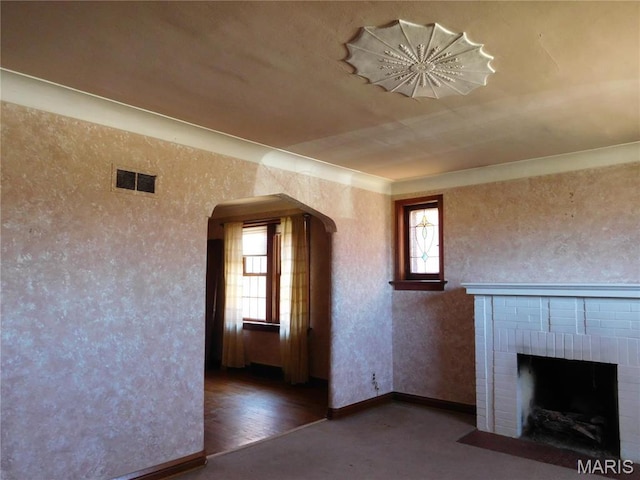 6432 Lansdowne Ave, Saint Louis, MO 63109 - unfurnished living room featuring arched walkways, a brick fireplace, and baseboards