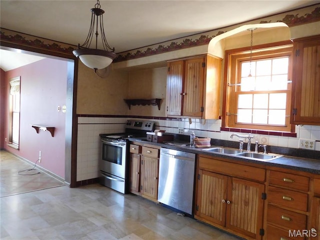 6432 Lansdowne Ave, Saint Louis, MO 63109 - kitchen featuring appliances with stainless steel finishes, a sink, dark countertops, light flooring, and decorative light fixtures