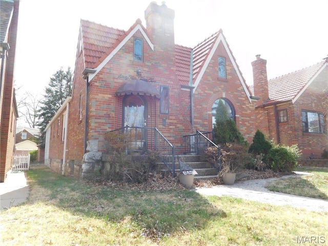 6432 Lansdowne Ave, Saint Louis, MO 63109 - tudor-style house featuring a chimney, brick siding, a tile roof, and a front yard