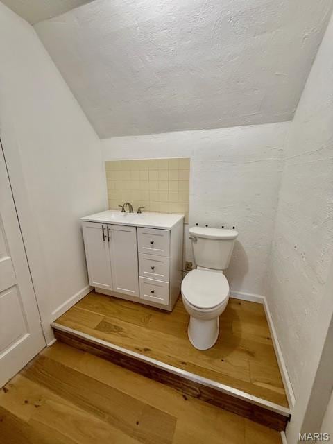201 W Barr Ave, Jerseyville, IL 62052 - half bathroom featuring lofted ceiling, wood finished floors, vanity, toilet, and baseboards