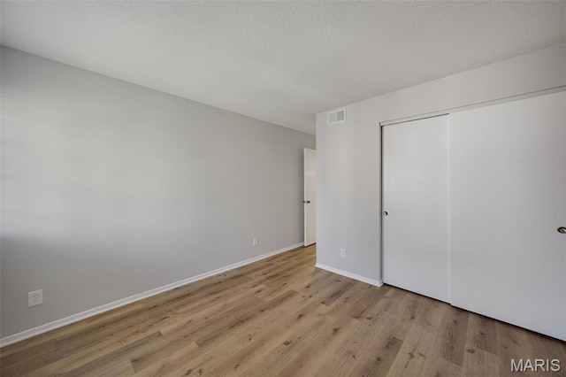 1420 Heritage Lndg Unit 207, Saint Charles, MO 63303 - unfurnished bedroom featuring wood finished floors, a closet, baseboards, and a textured ceiling
