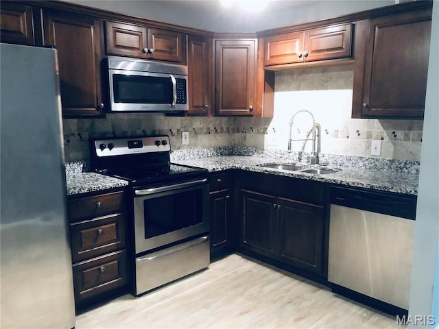 6990 Colonial Woods Dr Unit 59, Saint Louis, MO 63129 - kitchen with appliances with stainless steel finishes, a sink, backsplash, light stone counters, and light wood-style floors