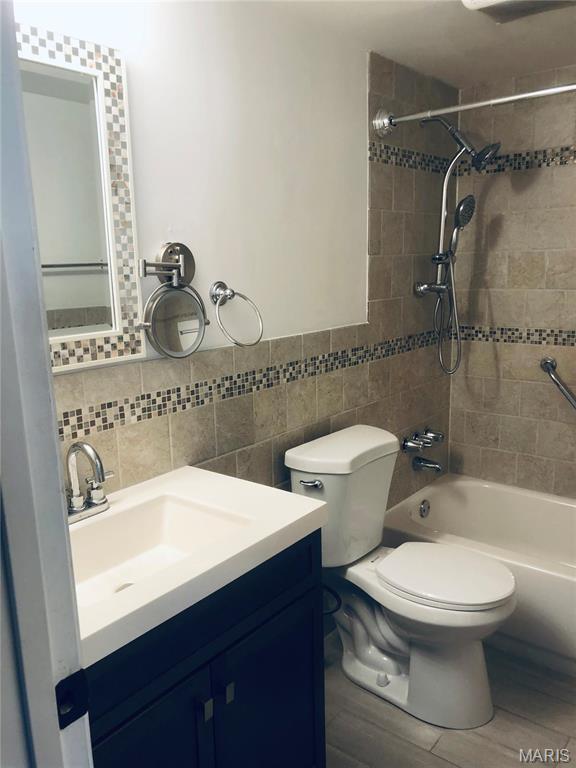 6990 Colonial Woods Dr Unit 59, Saint Louis, MO 63129 - full bath with tile walls, bathtub / shower combination, vanity, toilet, and wood finished floors