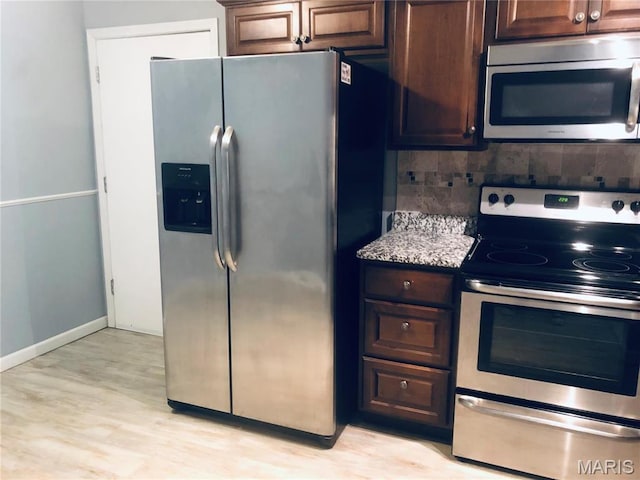 6990 Colonial Woods Dr Unit 59, Saint Louis, MO 63129 - kitchen featuring stainless steel appliances, light wood finished floors, baseboards, dark brown cabinets, and light stone counters