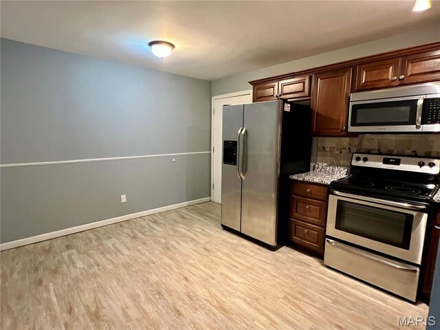 6990 Colonial Woods Dr Unit 59, Saint Louis, MO 63129 - kitchen with appliances with stainless steel finishes, light wood finished floors, backsplash, baseboards, and light stone countertops