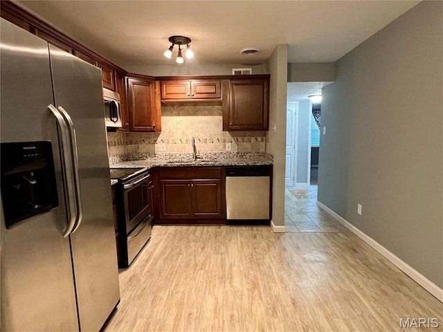 6990 Colonial Woods Dr Unit 59, Saint Louis, MO 63129 - kitchen with appliances with stainless steel finishes, a sink, decorative backsplash, light stone countertops, and light wood-style flooring
