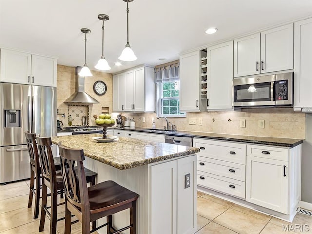 157 Knob Creek Ln, Ofallon, IL 62269 - kitchen with appliances with stainless steel finishes, wall chimney exhaust hood, light tile patterned floors, decorative backsplash, and a center island