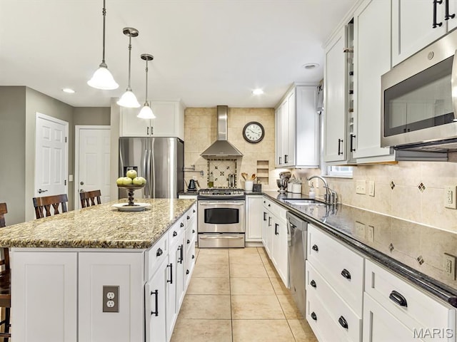 157 Knob Creek Ln, Ofallon, IL 62269 - kitchen featuring wall chimney range hood, stainless steel appliances, backsplash, dark stone counters, and a kitchen island