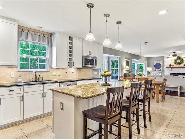 157 Knob Creek Ln, Ofallon, IL 62269 - kitchen featuring stainless steel microwave, light tile patterned flooring, open floor plan, backsplash, and healthy amount of natural light