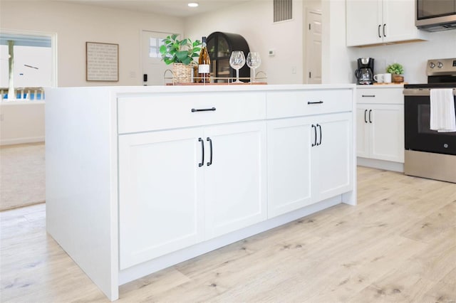 407 Front St, Monroe City, MO 63456 - kitchen with appliances with stainless steel finishes, white cabinets, light wood finished floors, and recessed lighting