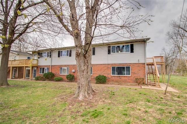 view of front facade with brick siding, stairway, a front yard, and a wooden deck