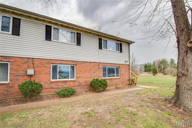 view of side of property with brick siding and a yard