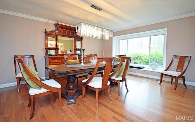 dining room featuring a chandelier, baseboards, light wood finished floors, and crown molding