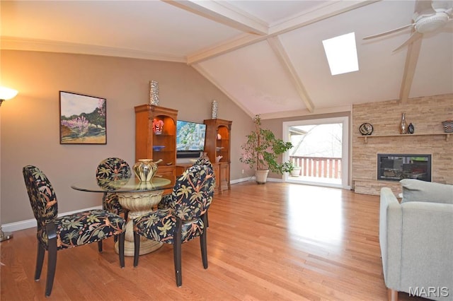 dining area with baseboards, a skylight, light wood-style flooring, and a ceiling fan