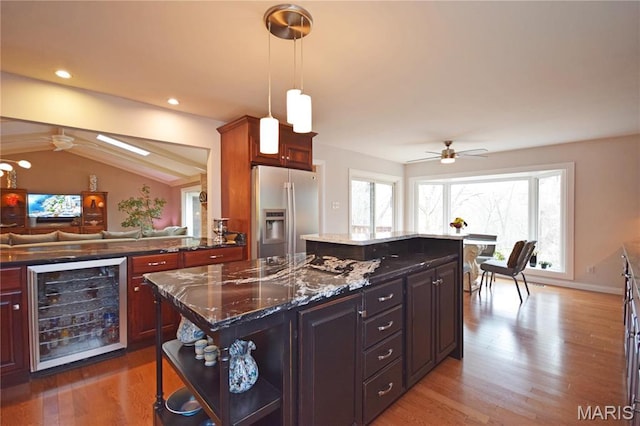 kitchen with stainless steel fridge with ice dispenser, wine cooler, ceiling fan, a center island, and light wood-type flooring