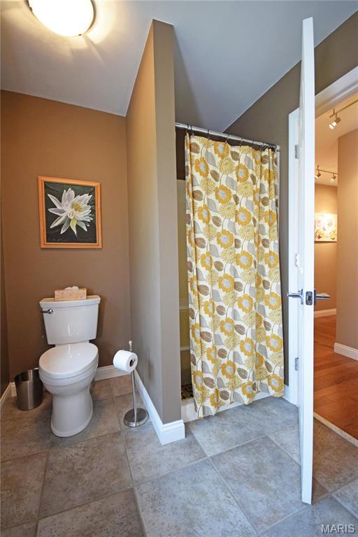 full bath with toilet, baseboards, a shower with shower curtain, and tile patterned floors