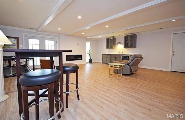 interior space featuring beam ceiling, baseboards, light wood-style floors, bar, and recessed lighting