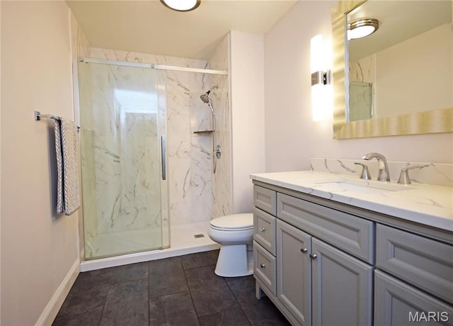 bathroom with a marble finish shower, toilet, vanity, and baseboards