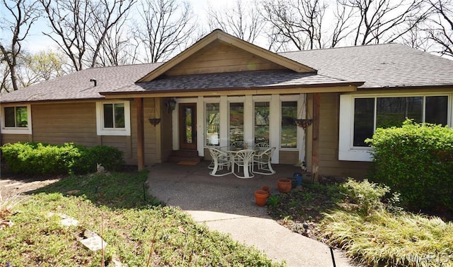view of front of house with a shingled roof and a patio area