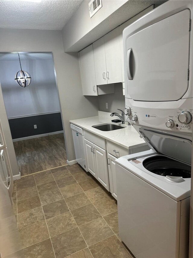 1459 Bobolink Pl, Saint Louis, MO 63144 - laundry area with stacked washer / dryer, cabinet space, baseboards, and a textured ceiling