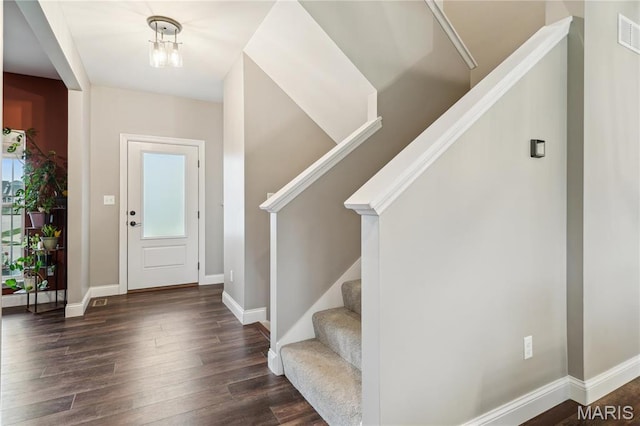 entryway featuring wood finished floors, baseboards, and stairs