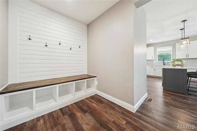 mudroom featuring dark wood-type flooring, baseboards, a sink, and recessed lighting