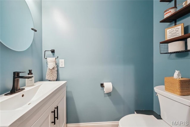 bathroom featuring toilet, vanity, and baseboards