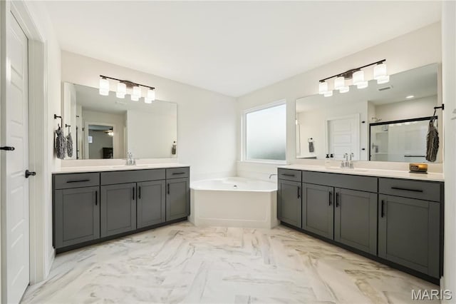 full bathroom featuring a shower stall, a garden tub, two vanities, and marble look tile flooring