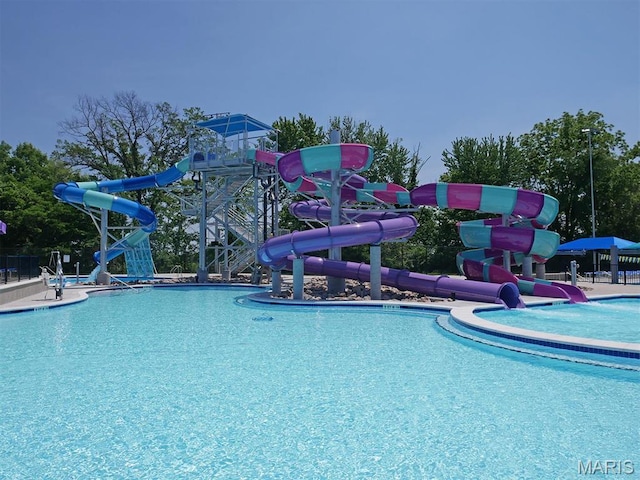 community pool featuring a water slide and fence