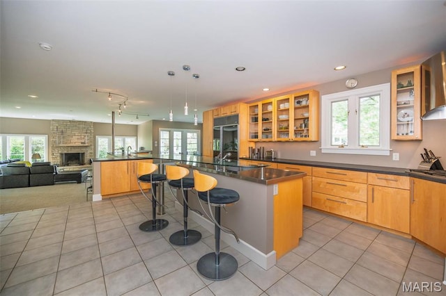 1211 S Geyer Rd, Saint Louis, MO 63122 - kitchen featuring light tile patterned floors, a breakfast bar, dark countertops, open floor plan, and wall chimney range hood