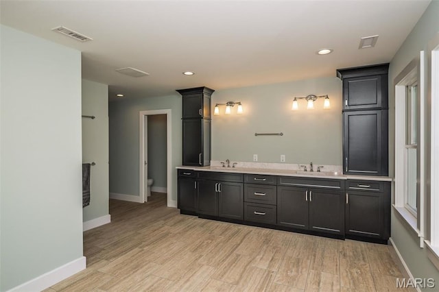 1211 S Geyer Rd, Saint Louis, MO 63122 - bathroom featuring double vanity, wood finished floors, toilet, baseboards, and recessed lighting