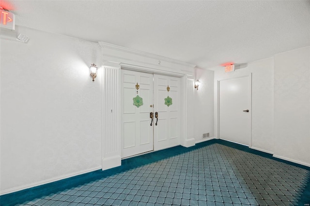 entryway with dark carpet, baseboards, and a textured ceiling