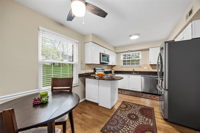 kitchen featuring appliances with stainless steel finishes, dark countertops, a peninsula, white cabinetry, and a textured ceiling