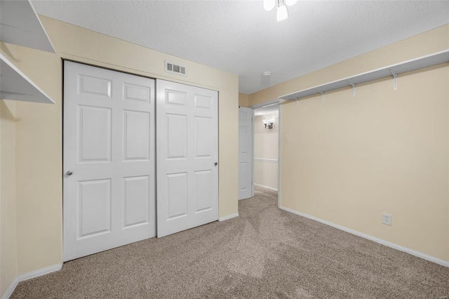 unfurnished bedroom featuring carpet flooring, a closet, baseboards, and a textured ceiling