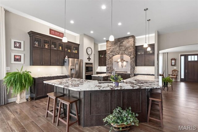 408 Hamlet Ct, Lake St Louis, MO 63367 - kitchen with appliances with stainless steel finishes, a large island with sink, a kitchen breakfast bar, dark wood-type flooring, and dark brown cabinets