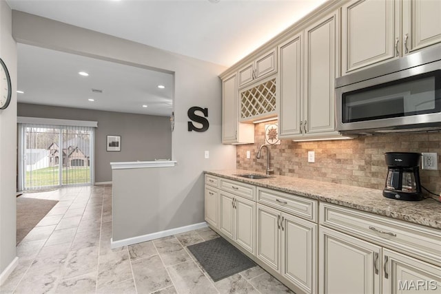 408 Hamlet Ct, Lake St Louis, MO 63367 - kitchen with stainless steel microwave, cream cabinets, decorative backsplash, light stone countertops, and recessed lighting