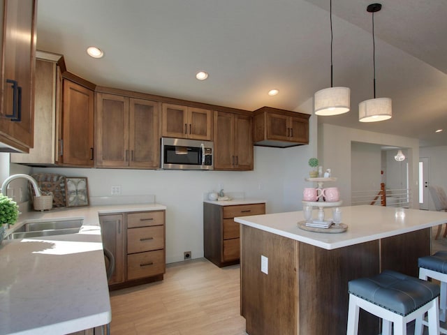 504 Timber View Ter, Hannibal, MO 63401 - kitchen with stainless steel microwave, a sink, a kitchen island, brown cabinets, and light wood-style flooring