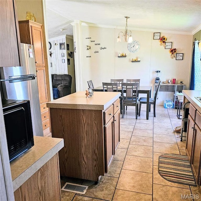 404 Garden St, Cahokia, IL 62206 - kitchen with ornamental molding, black microwave, light countertops, a center island, and a chandelier