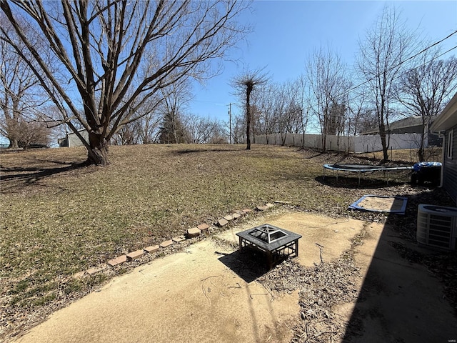 view of yard featuring a trampoline, a fire pit, cooling unit, and fence