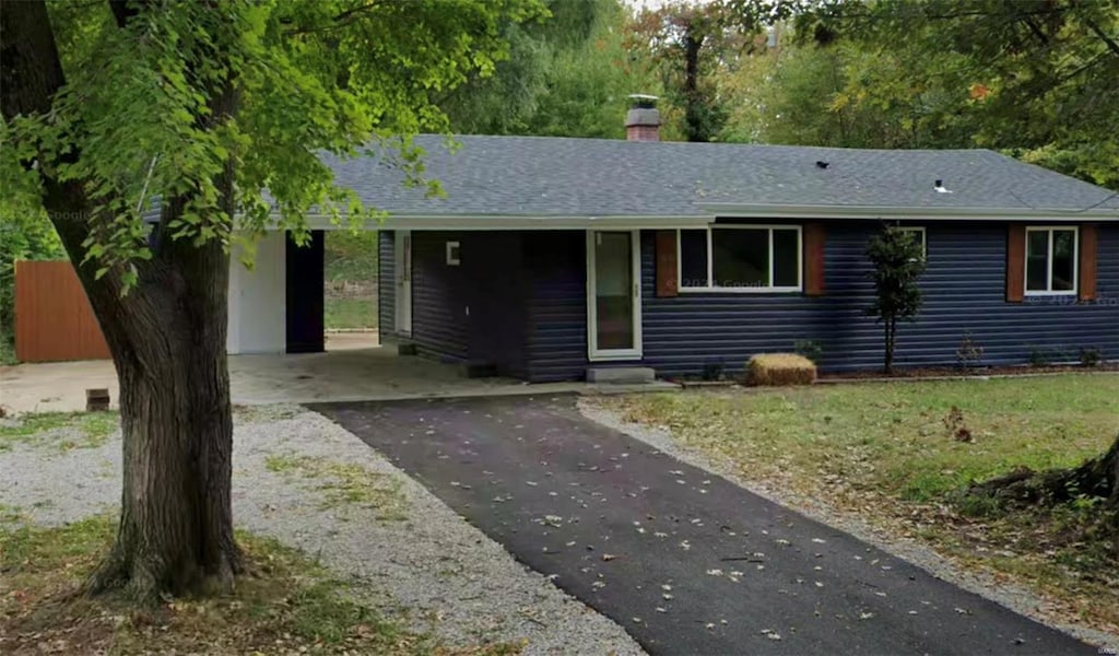 ranch-style house featuring a chimney, asphalt driveway, roof with shingles, a carport, and entry steps