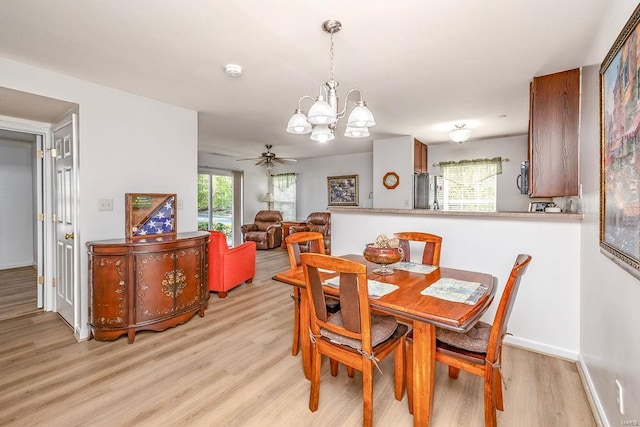 dining room with light wood-style floors, a chandelier, baseboards, and ceiling fan