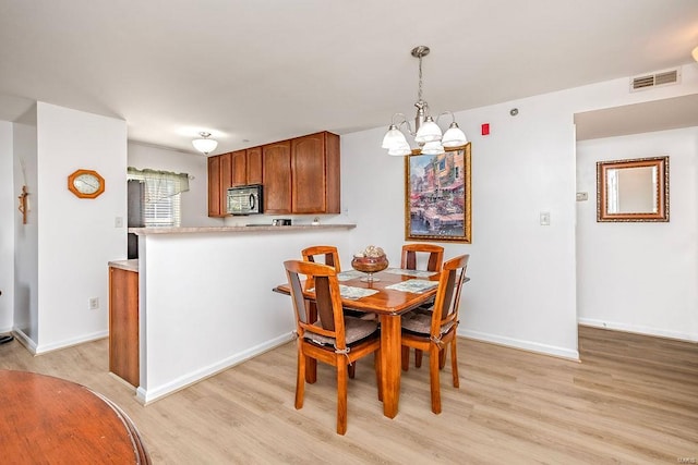 dining space featuring a chandelier, light wood-type flooring, and baseboards