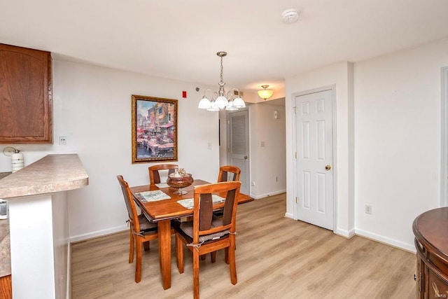 dining space with light wood-style floors, a chandelier, and baseboards