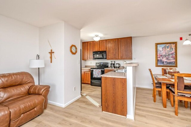 kitchen with black appliances, open floor plan, light countertops, baseboards, and light wood-style flooring