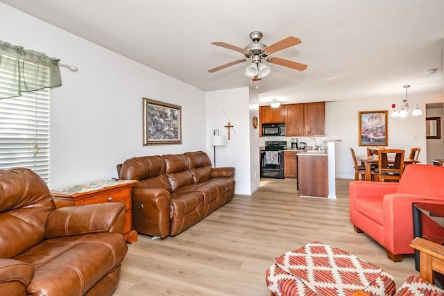 living area featuring a chandelier, ceiling fan, and light wood-style flooring