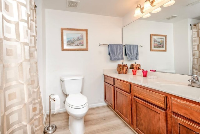 bathroom with wood finished floors, toilet, vanity, and baseboards